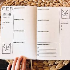 a person holding a pen and looking at an open planner on top of a basket