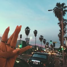 a person's hand with two fingers up in the air on a city street