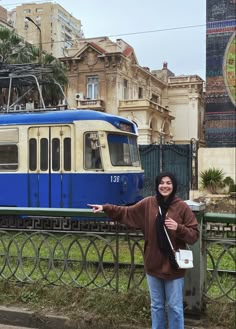 a woman standing in front of a blue and white train