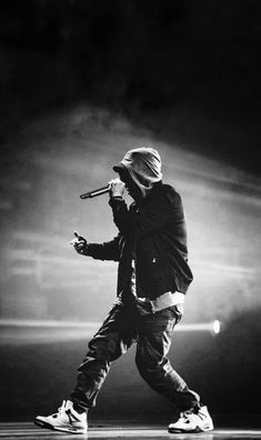 a black and white photo of a person holding a microphone in his right hand while standing on stage