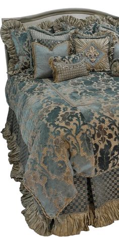 a bed covered in blue and gold comforter with ruffles on the bottom