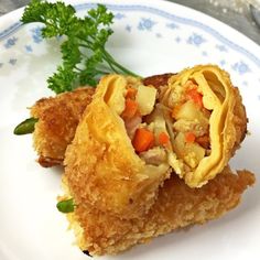 two fried food items on a white and blue plate with parsley sprig