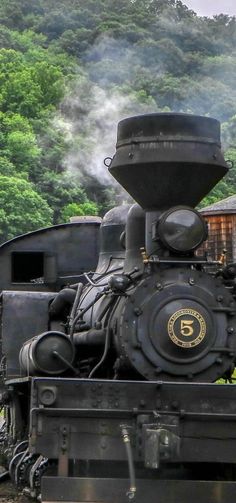 an old fashioned steam engine sitting on the tracks