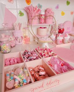 a table filled with lots of candy and candies on top of each other in pink boxes