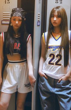 two young women standing next to each other in front of lockers wearing basketball uniforms