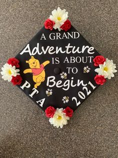 a graduation cap decorated with pooh the pooh bear and flowers is on the ground