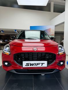 the front end of a red car in a showroom