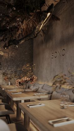 an empty restaurant with wooden tables and gray couches in front of a stone wall