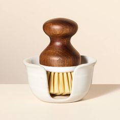 a wooden brush in a white bowl on a table