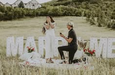 a man kneeling down next to a woman in front of a sign that says married