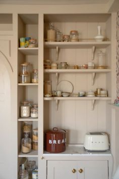 a kitchen with white cabinets and shelves filled with food