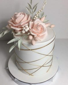 there is a white cake with pink flowers on top and gold wire around the edges