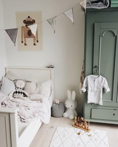 a bed room with a neatly made bed and stuffed animals on the floor next to it