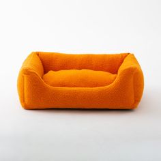 an orange dog bed sitting on top of a white floor