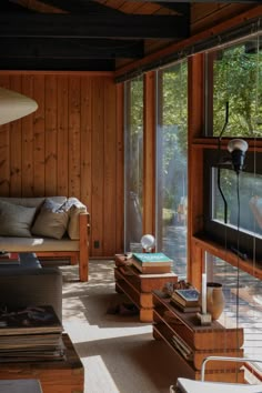 a living room with wood paneling and windows looking out onto the backyard area outside