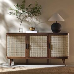 a sideboard with wicker doors and a lamp next to it on a carpeted floor