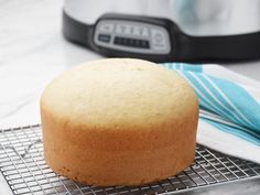 a cake sitting on top of a cooling rack next to an electric pressure cooker