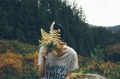 a person holding a plant in front of their face with the words happy camp written on it