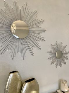 two sunburst mirrors on the wall above vases