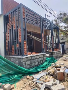 a house under construction with green tarp on the ground and brick walls around it