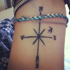 a woman's arm with a compass tattoo on it and two bracelets around her wrist