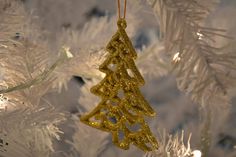 a gold christmas tree ornament hanging from a white christmas tree