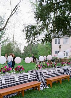 an outdoor table set up with black and white checkered cloths, paper lanterns and pink flowers