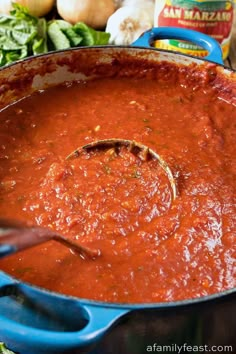 a blue pot filled with red sauce next to vegetables