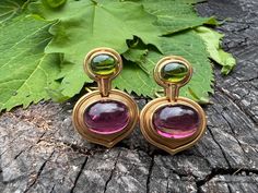 "These bold earrings are set in 18k yellow gold and drenched in sophistication.  They date from the 1980's.  The oval shaped  mounting  has  beautifully scrolled rims of gold that come to a point, acting as the  backdrop that hold,  in the center,  a deep rich oval pink tourmaline.  Right above the pink tourmaline is an oval  shaped forest green tourmaline. All set east to west creating the chicness.    The pink tourmaline measures approx. 11 mm x 14 mm.   The green tourmaline measures 6.5 mm x Luxury Tourmaline Dangle Jewelry, Luxury Classic Tourmaline Jewelry, Tourmaline Earrings, Bold Earrings, Earrings Pink, Green Tourmaline, Pink Tourmaline, The Pink, Forest Green