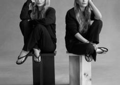 two women sitting on top of wooden blocks with their hands behind their heads and one holding her head