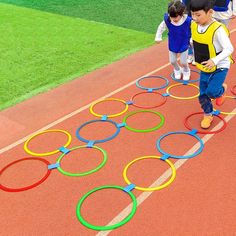 two children are walking on the track made out of circles and plastic hoop rings, while another child is running behind them