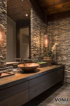 a bathroom with stone walls and a wooden counter top, along with a vessel sink