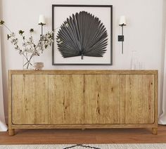 a large wooden cabinet sitting in front of a painting on the wall next to a vase with flowers