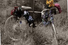 an old bicycle with flowers on the front and back wheel is parked in tall grass