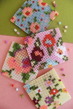 three pieces of beaded art on a pink surface