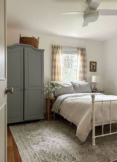 a bedroom with a bed, dresser and rug in the corner next to a window