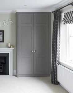 an empty room with a large gray cabinet next to a window and a fire place