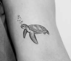 a small turtle tattoo on the right side of the arm, with bubbles coming out of it