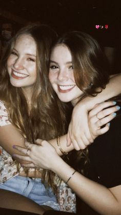 two young women hugging each other while sitting down