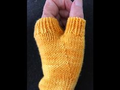 someone is holding their hand up to show the yellow knitted fingerless mitts