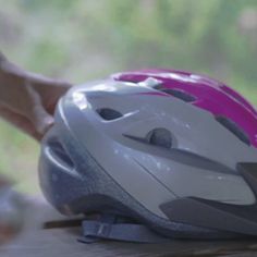 a helmet sitting on top of a wooden table next to a person's hand