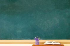 an open book on a desk in front of a chalkboard