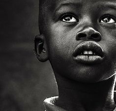 a black and white photo of a young boy with his eyes wide open, staring at the camera