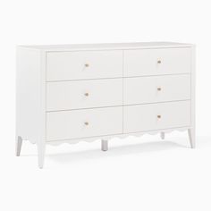 a white dresser with four drawers and two handles on each drawer, against a white background