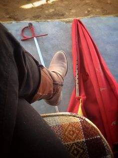 a person standing next to a red umbrella with a pair of boots on top of it