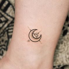 a small tattoo on the ankle of a woman's foot with a crescent moon and stars