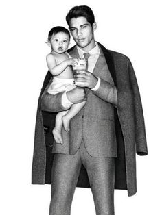 a black and white photo of a man in a suit holding a baby on his lap