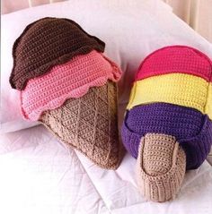 two crocheted ice cream cones are laying on a bed with white sheets and pillows