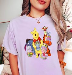 a woman wearing a purple winnie the pooh t - shirt with cartoon characters on it