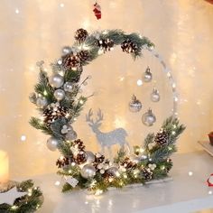 a christmas wreath with lights and ornaments on a mantle in front of a white wall